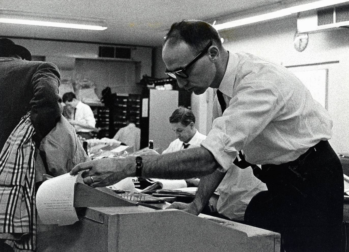 Gene Mater, director of news, reads an incoming bulletin on early developments in Dallas, following President Kennedy's assassination. November 22, 1963.